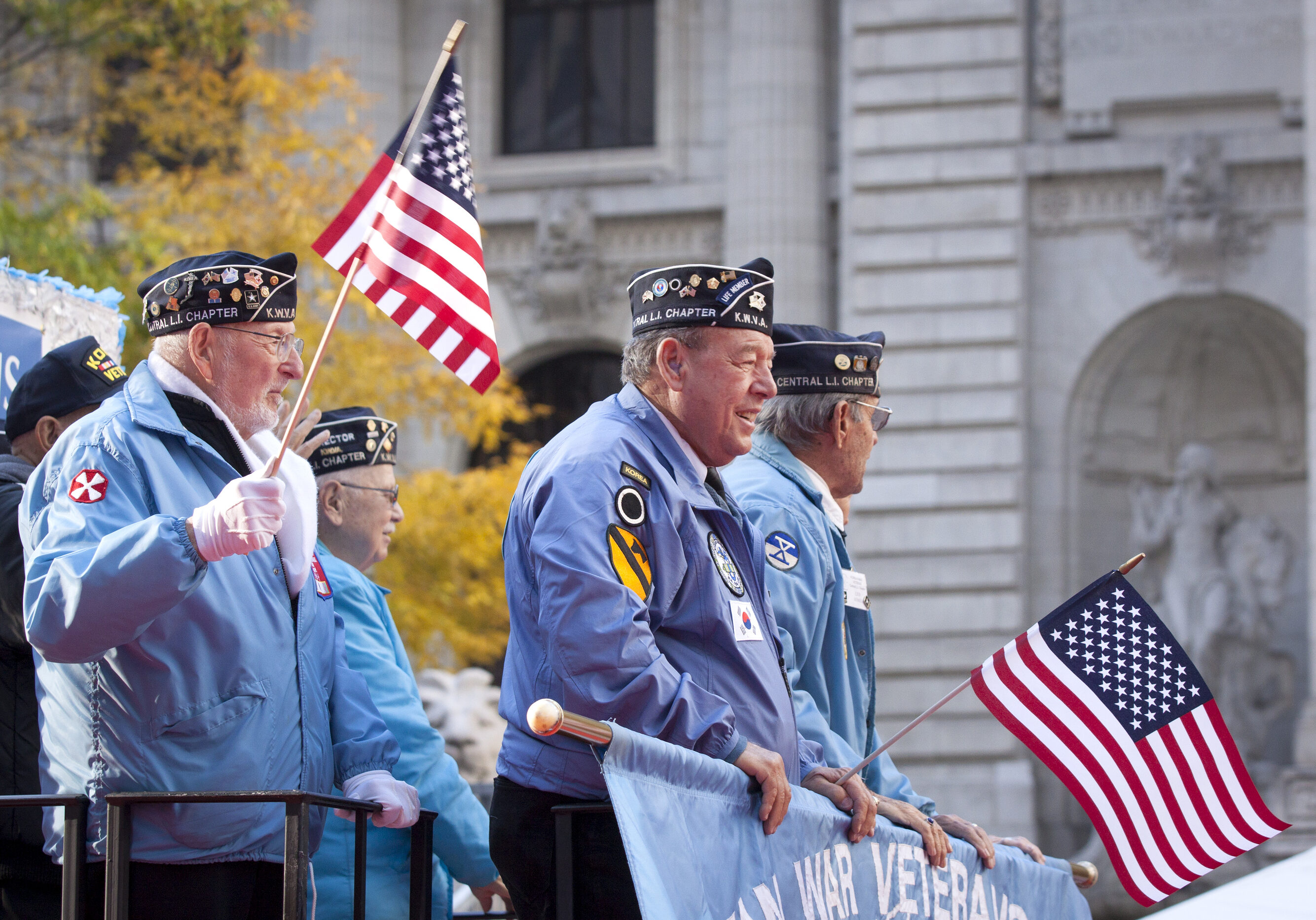 NEW YORK - NOV 11, 2014: US vets wave American Flags as they stand on a parade float in the 2014 America's Parade held on Veterans Day in New York City on November 11, 2014.